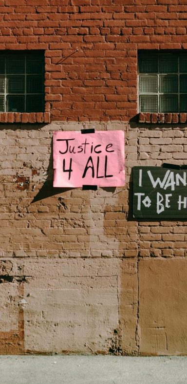 Brick wall with two posters: “Justice 4 All” and “I Want to Be Heard.”