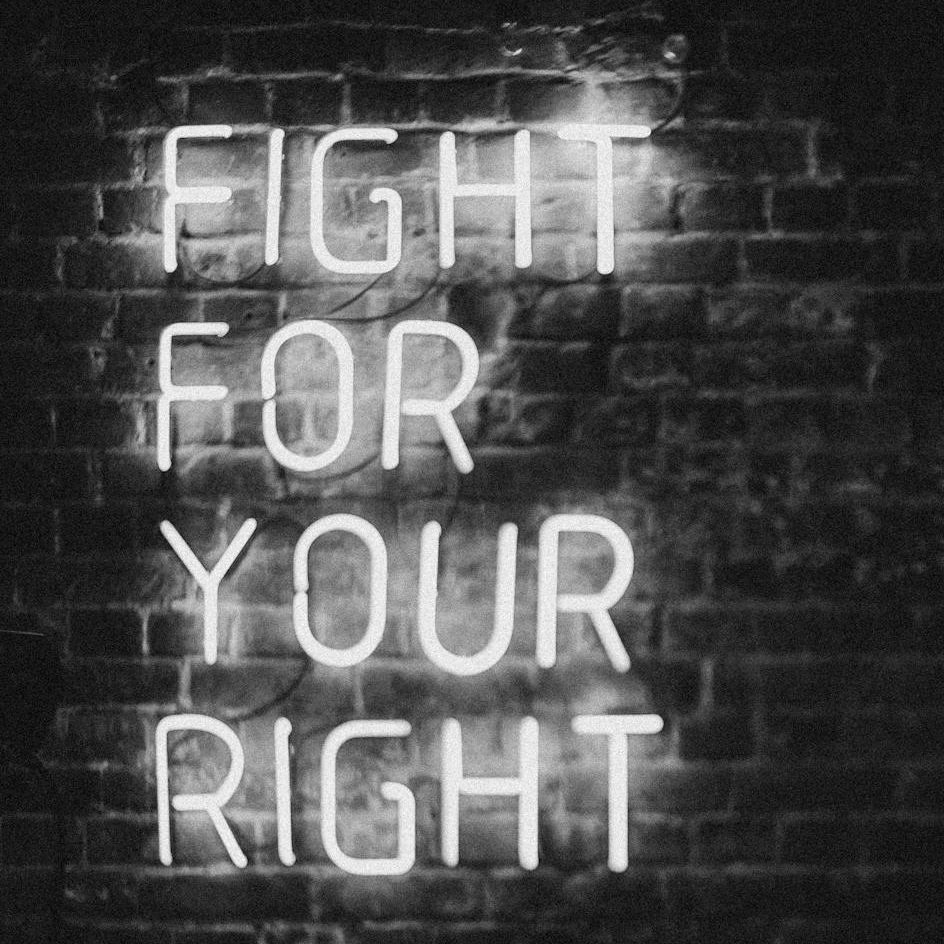 A black-and-white photo. White neon tubes glow in the words: Fight for your right.