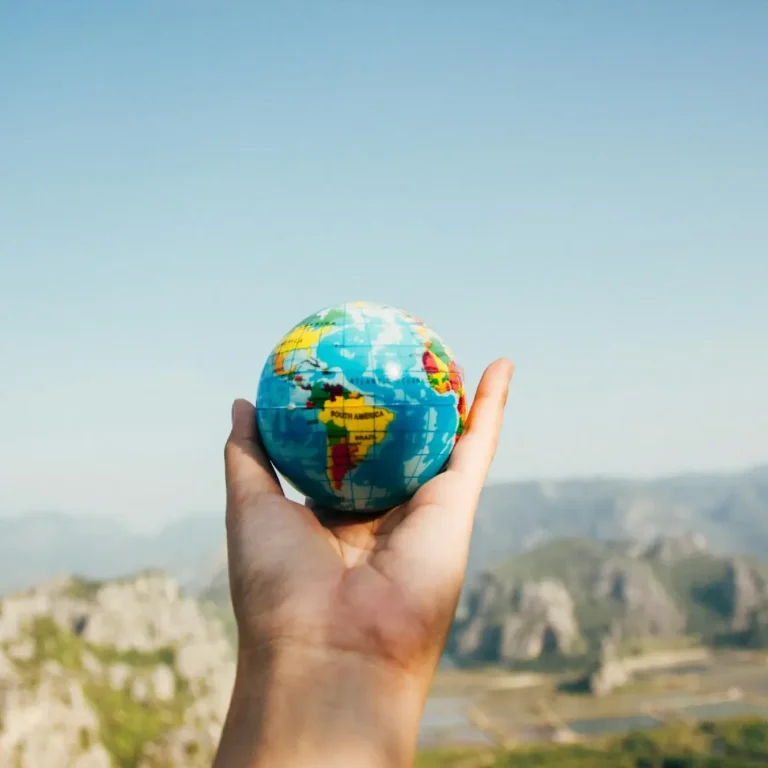 A hand holds a small globe, gently cradling the world in its palm.